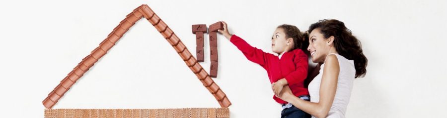 Illustrative image of a mother with her child lying next a house model made of mini bricks
