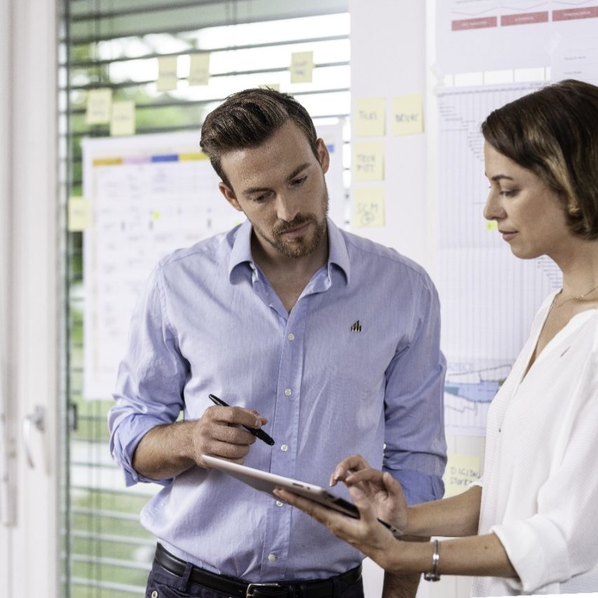 Male and female project manager in front of timeline sheets or project process maps at office